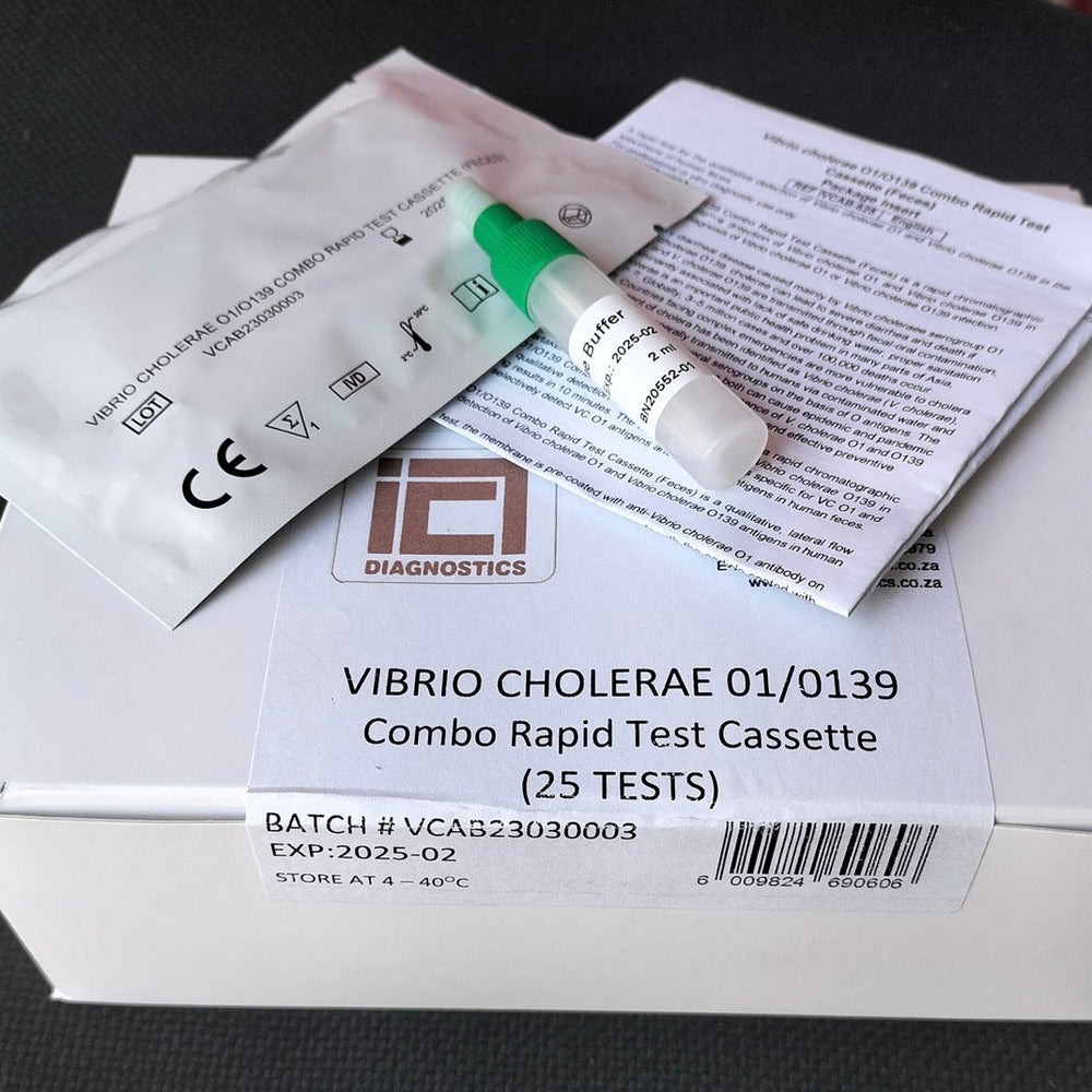 Vibrio cholerae combo rapid test cassette kit by iDiagnostics, showing the white outer box, a foil test pouch, a small test tube with a green cap, and printed instruction sheets on a dark surface.
