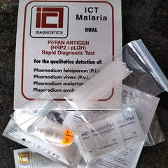 ICT Malaria Dual Test kit components including a white printed card, plastic bags, a small bottle, and alcohol pads arranged on a dark stone surface.